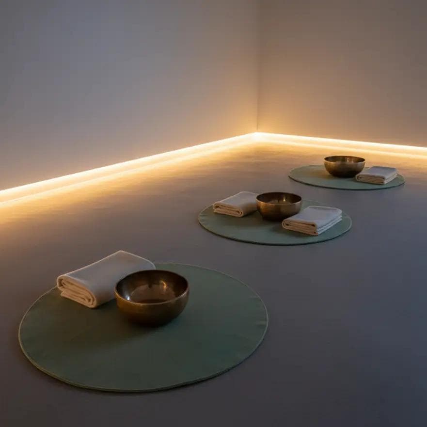 Calm studio with Tibetan singing bowls set on mats and soft ambient lighting.